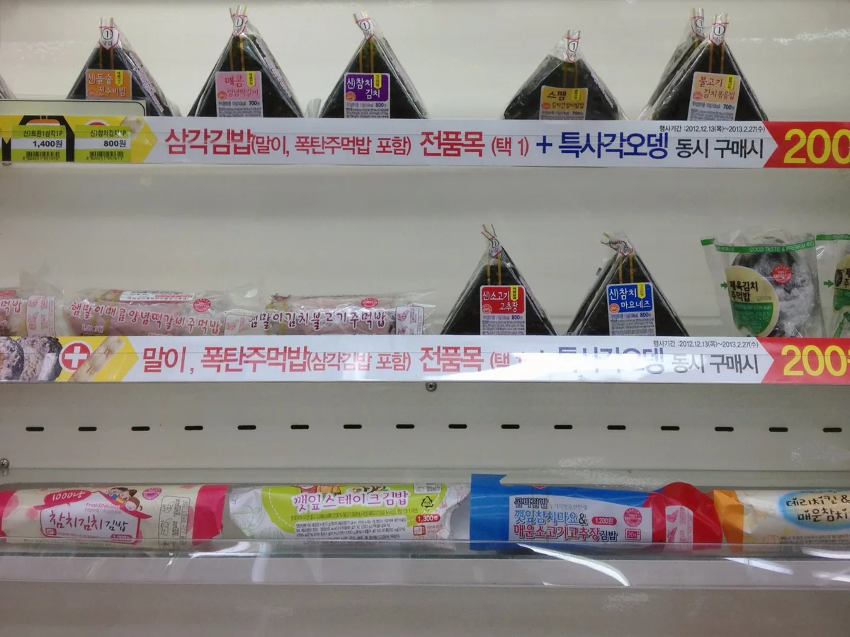 Triangle kimbap on a Korean convenience store shelf with Korean promotion tags