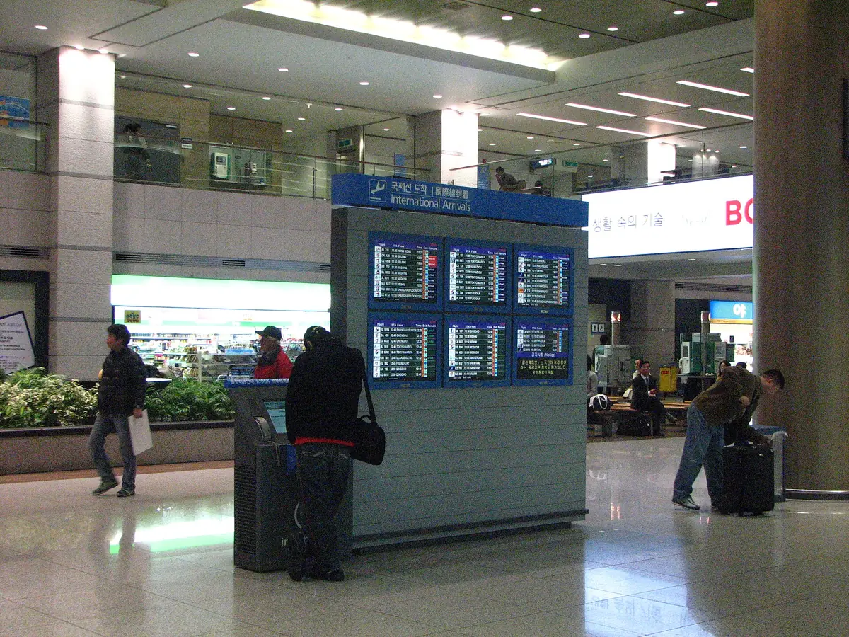 仁川國際機場入境大廳,旅客走過航班資訊看板