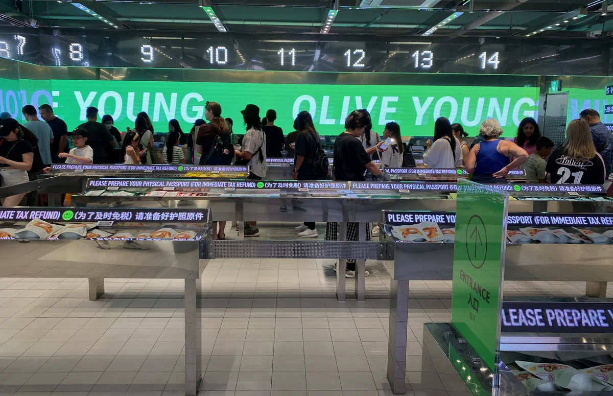Olive Young明洞店的結帳櫃台,掛著出示護照即時退稅的中英文告示