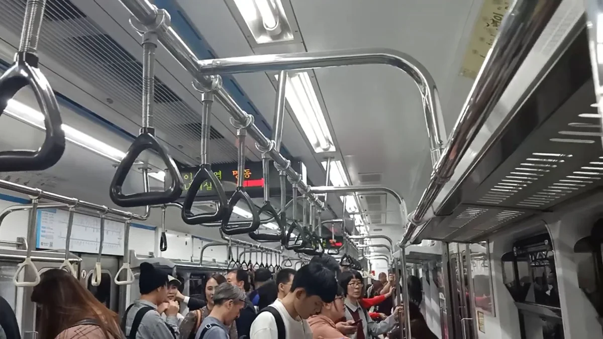 首爾地鐵4號線車廂內部，乘客與吊環