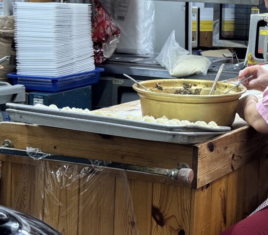 鐵盤上排成一列的生餃子,以及裝著餡料的盆子
