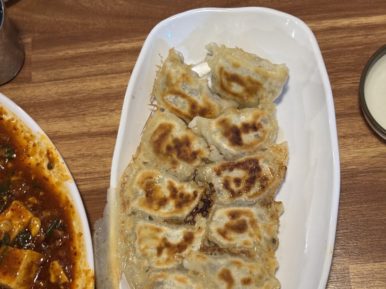 白盤裡的煎餃,旁邊放著麻婆豆腐