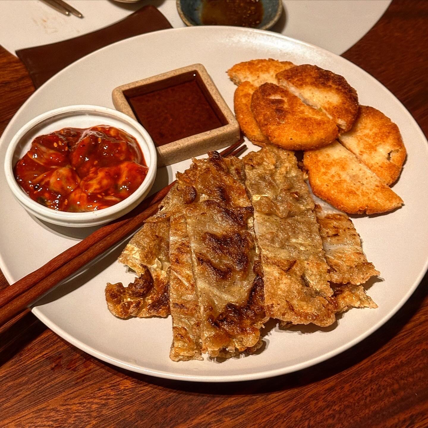 A plate of jeon stacked several deep with a dipping sauce