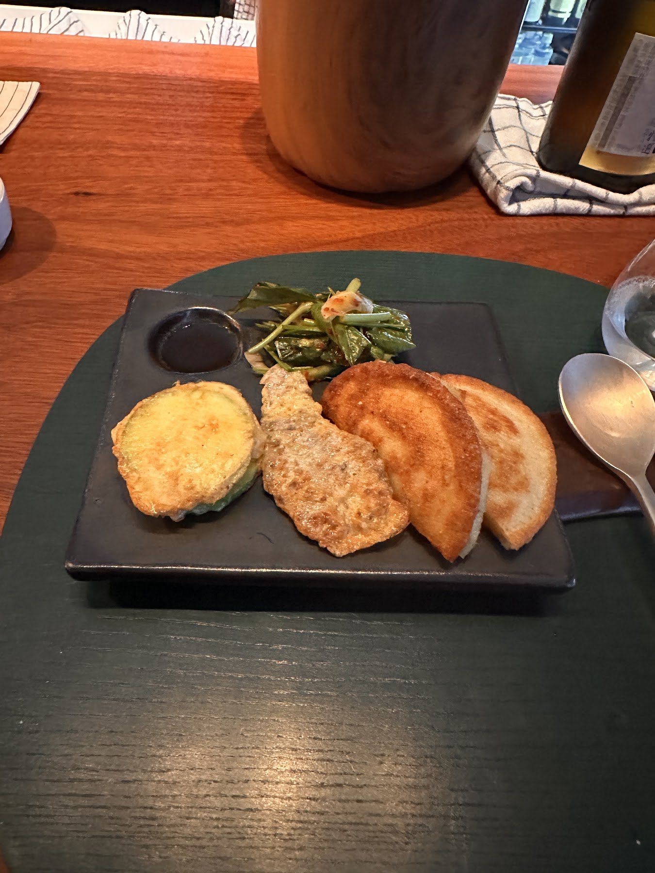 A black tray holding three kinds of jeon with namul