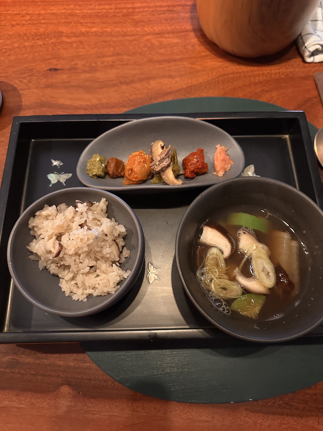 A table set with multigrain rice, clear soup and small side dishes