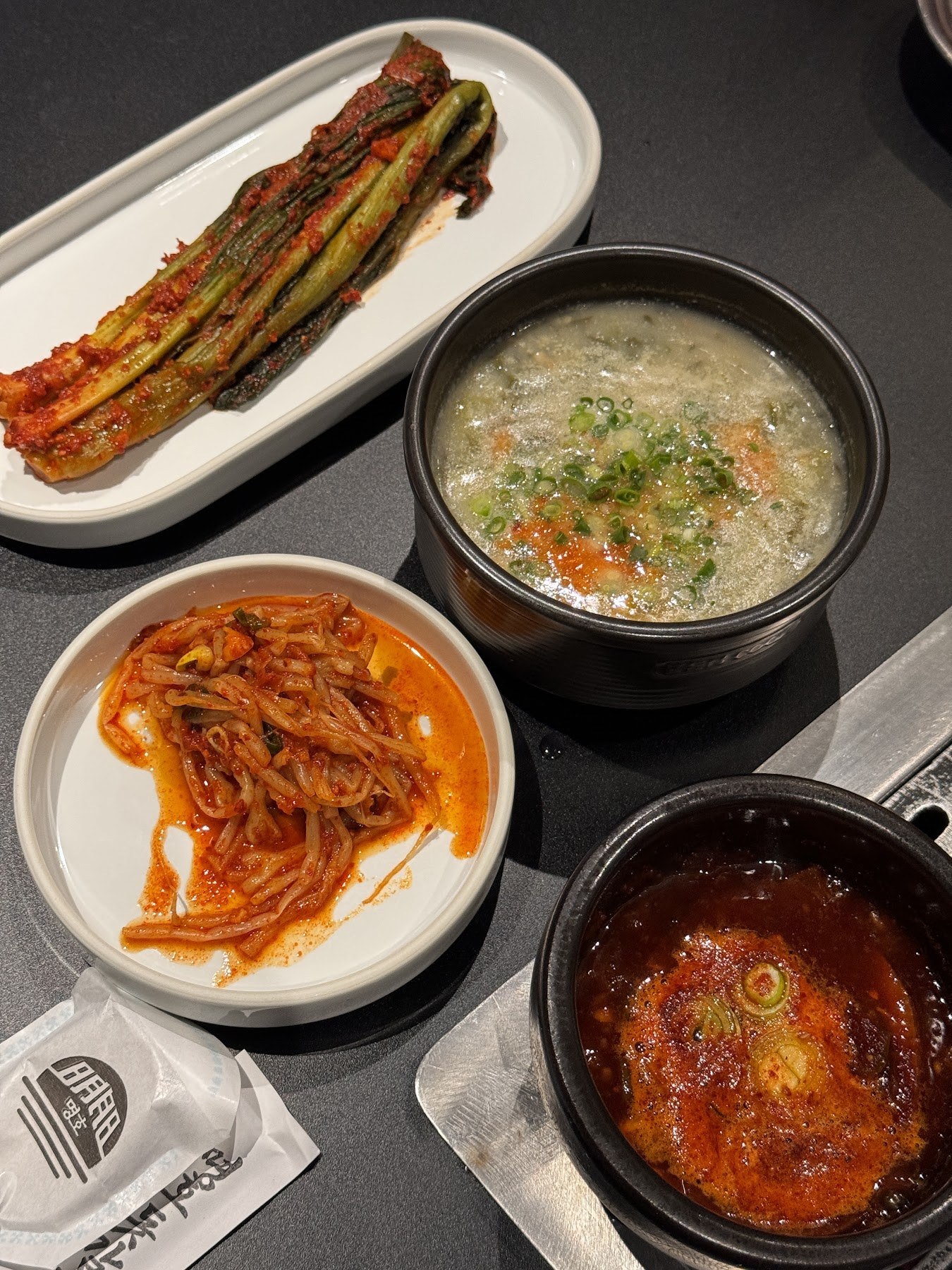 擺著涼拌蒜苔、泡菜、蒸蛋與湯的一桌