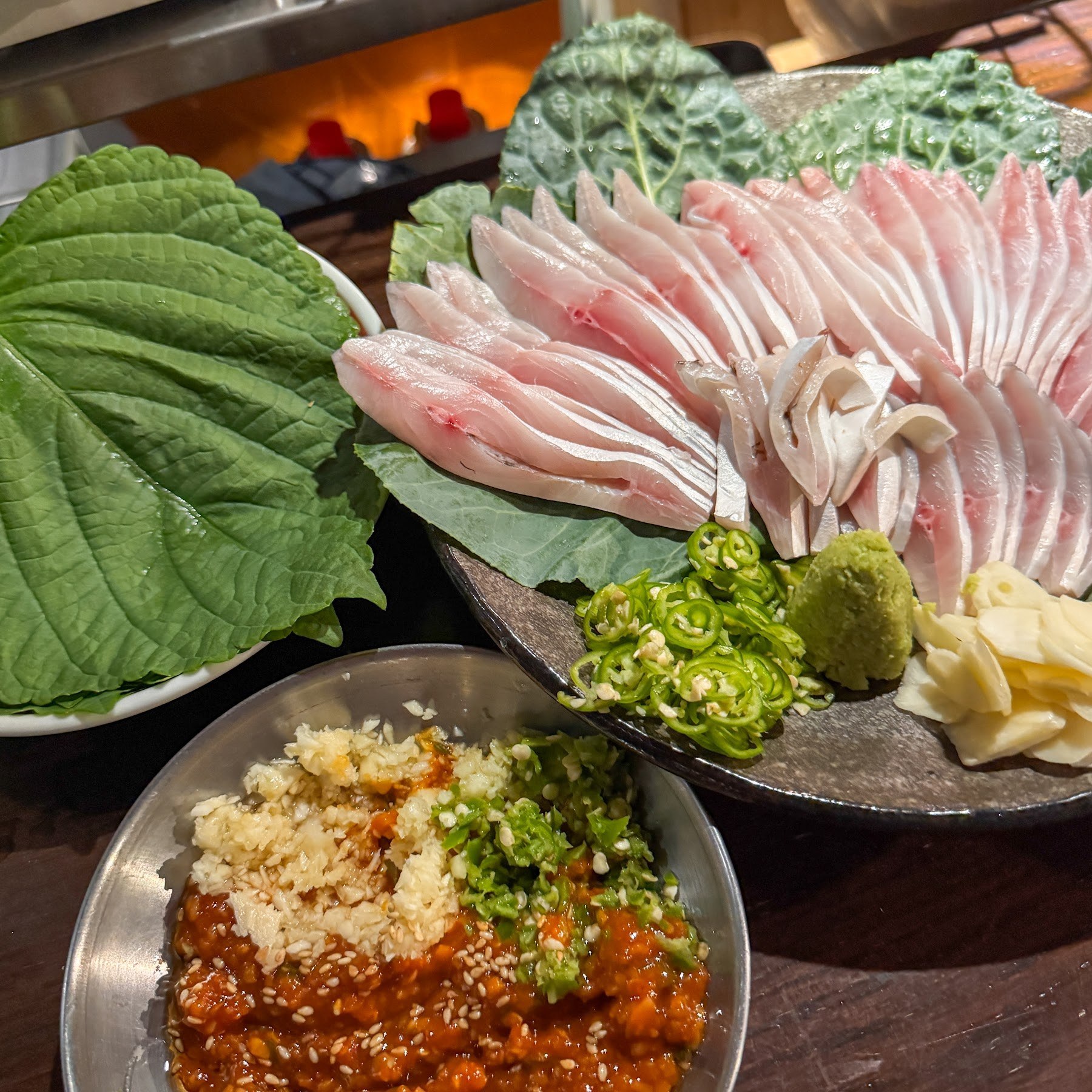 在紫蘇葉上鋪開白肉魚與紅肉魚的綜合生魚片