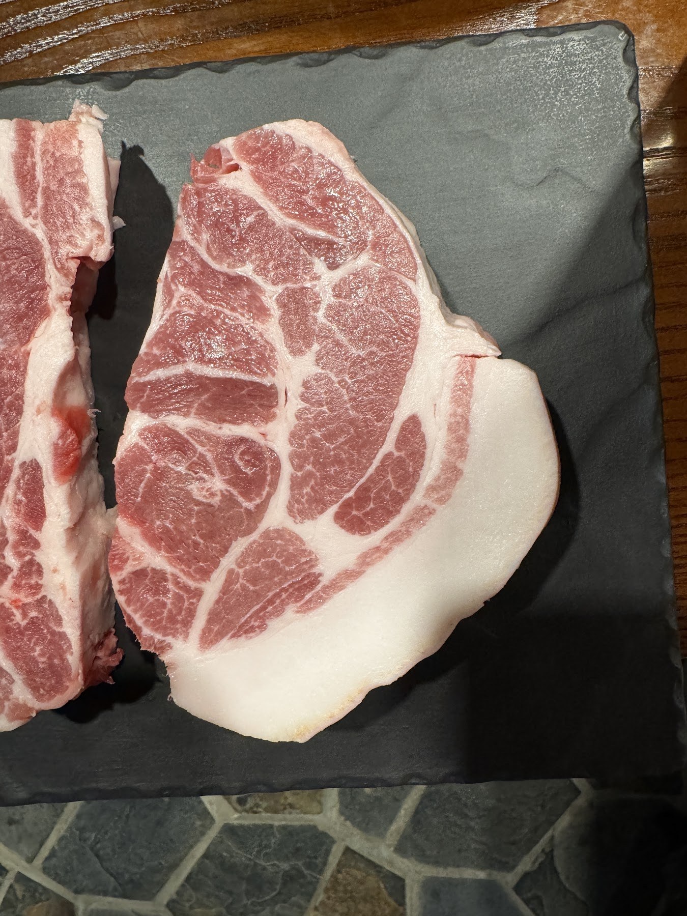 放在黑色石板上的五花肉與梅花肉兩大塊
