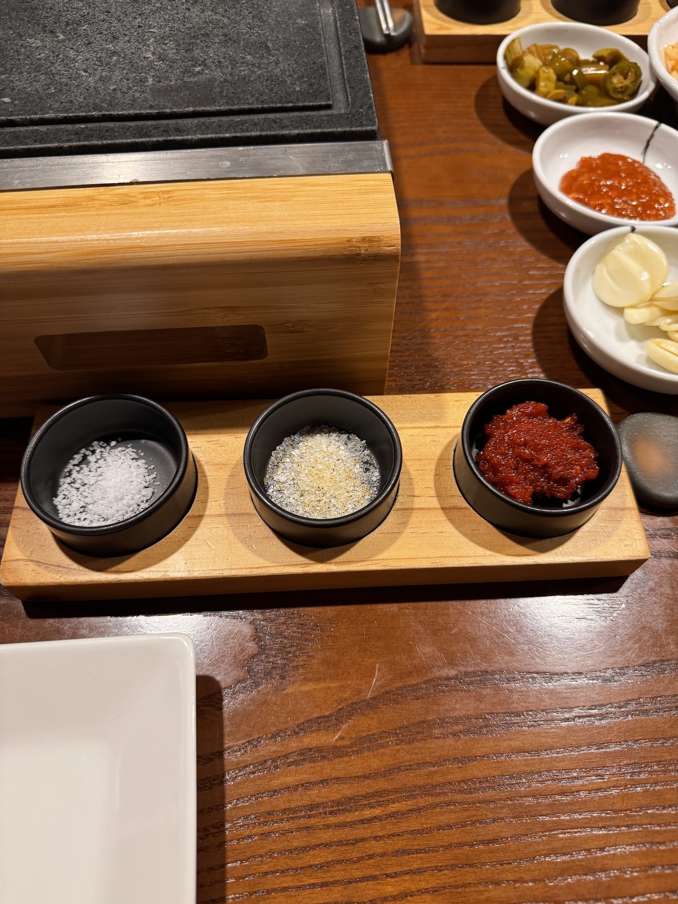 並排放在木板上的鹽、蒜泥與紅色醬料