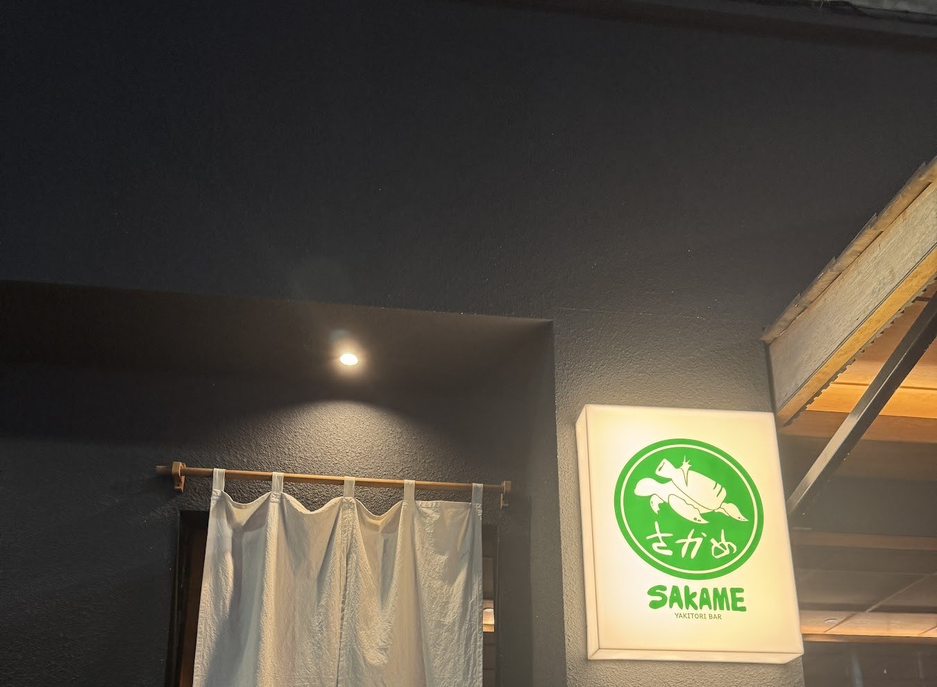 白色暖簾旁畫著烏龜的SAKAME招牌燈