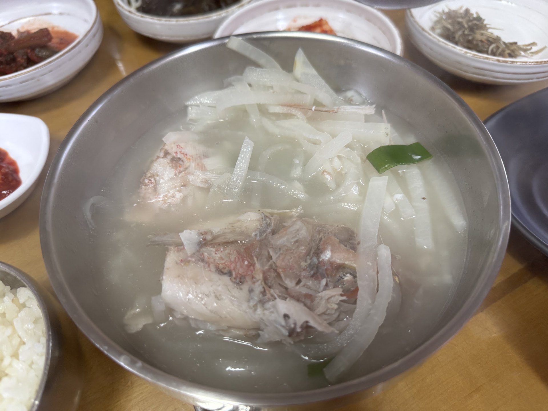 Clear fish soup with pieces of fish under shredded radish