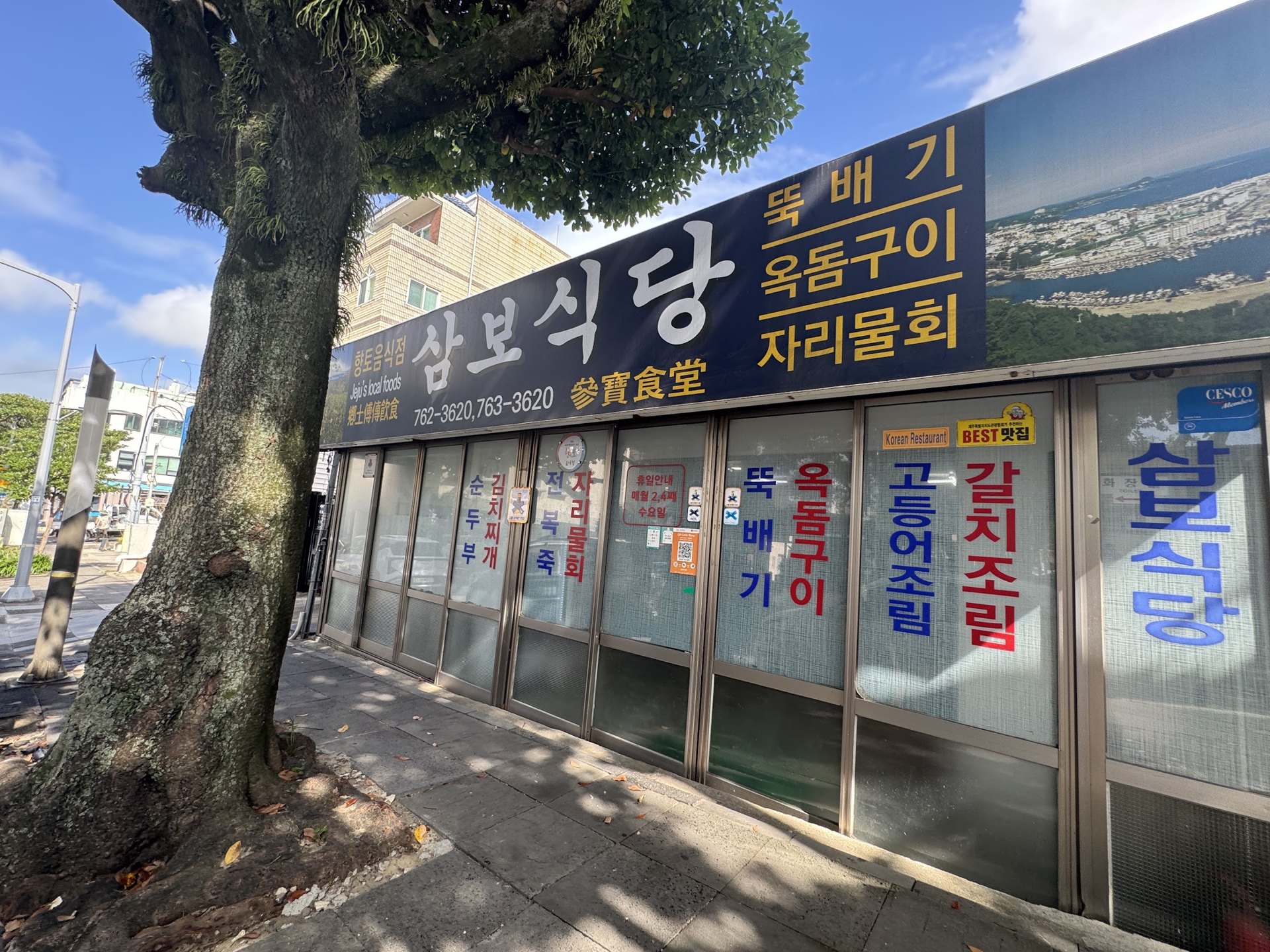 The exterior of Sambo Sikdang, with hotpot, grilled okdom and chari mulhoe posted on the front window