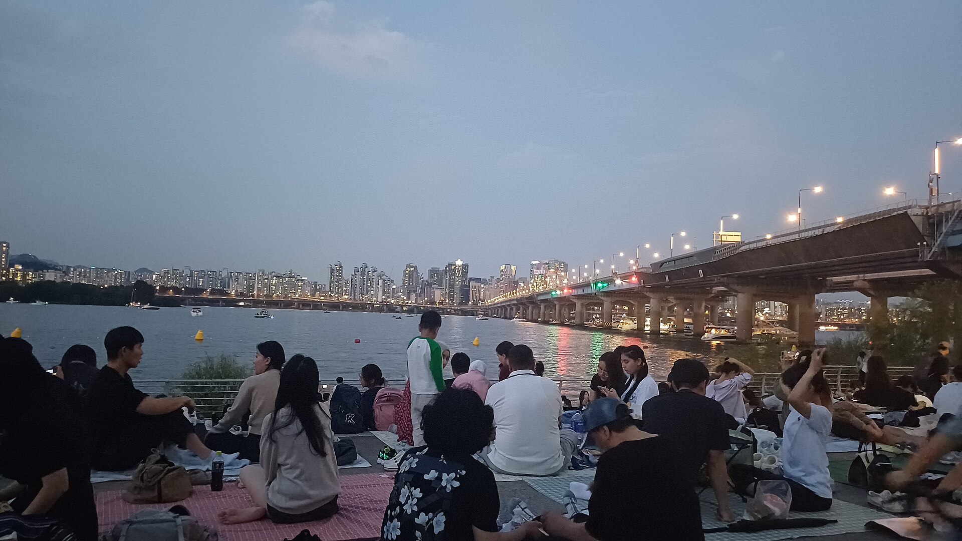 People picnicking on the Han River at dusk