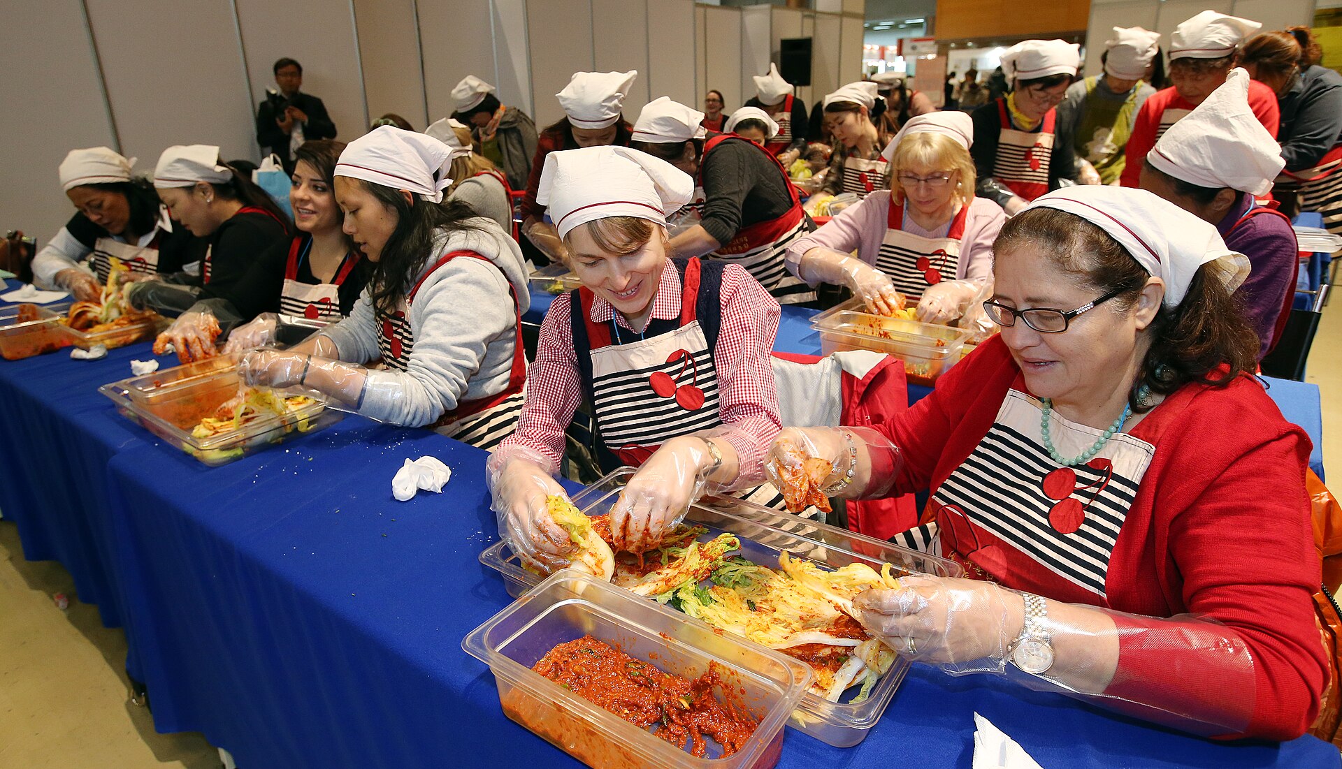 Class participants in aprons and gloves making kimchi