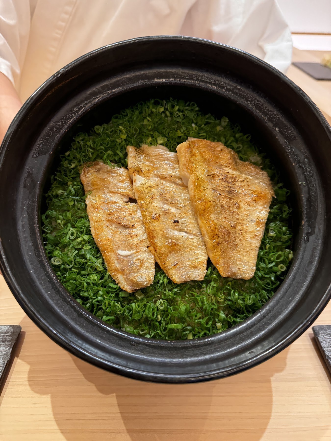 在綠色蔬菜上放烤魚一起炊煮的石鍋飯