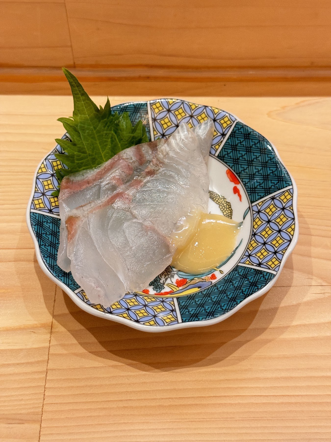 盛在青花白瓷盤上的白肉魚生魚片