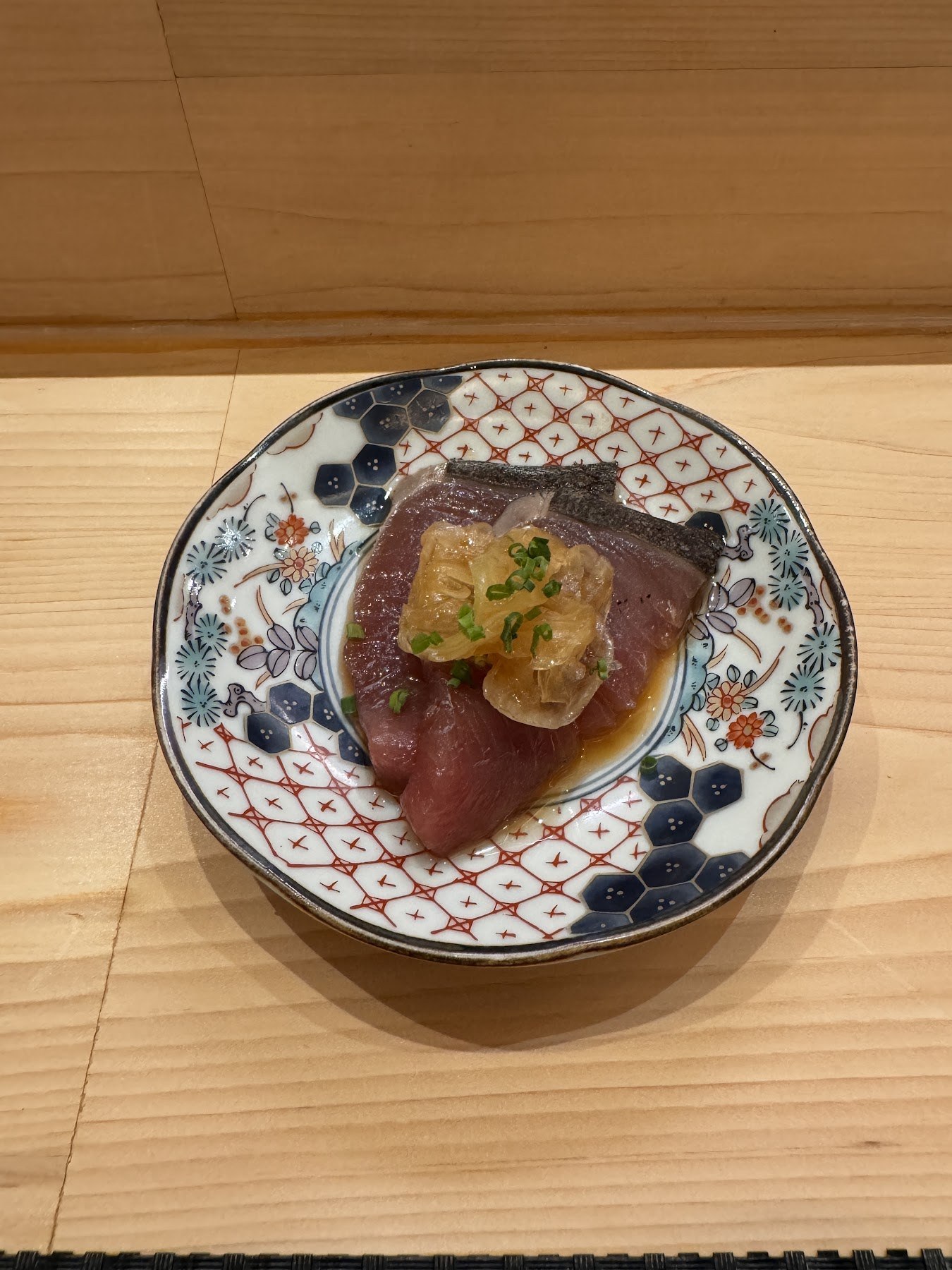 青花白瓷盤上放著紅肉與佐料的前菜