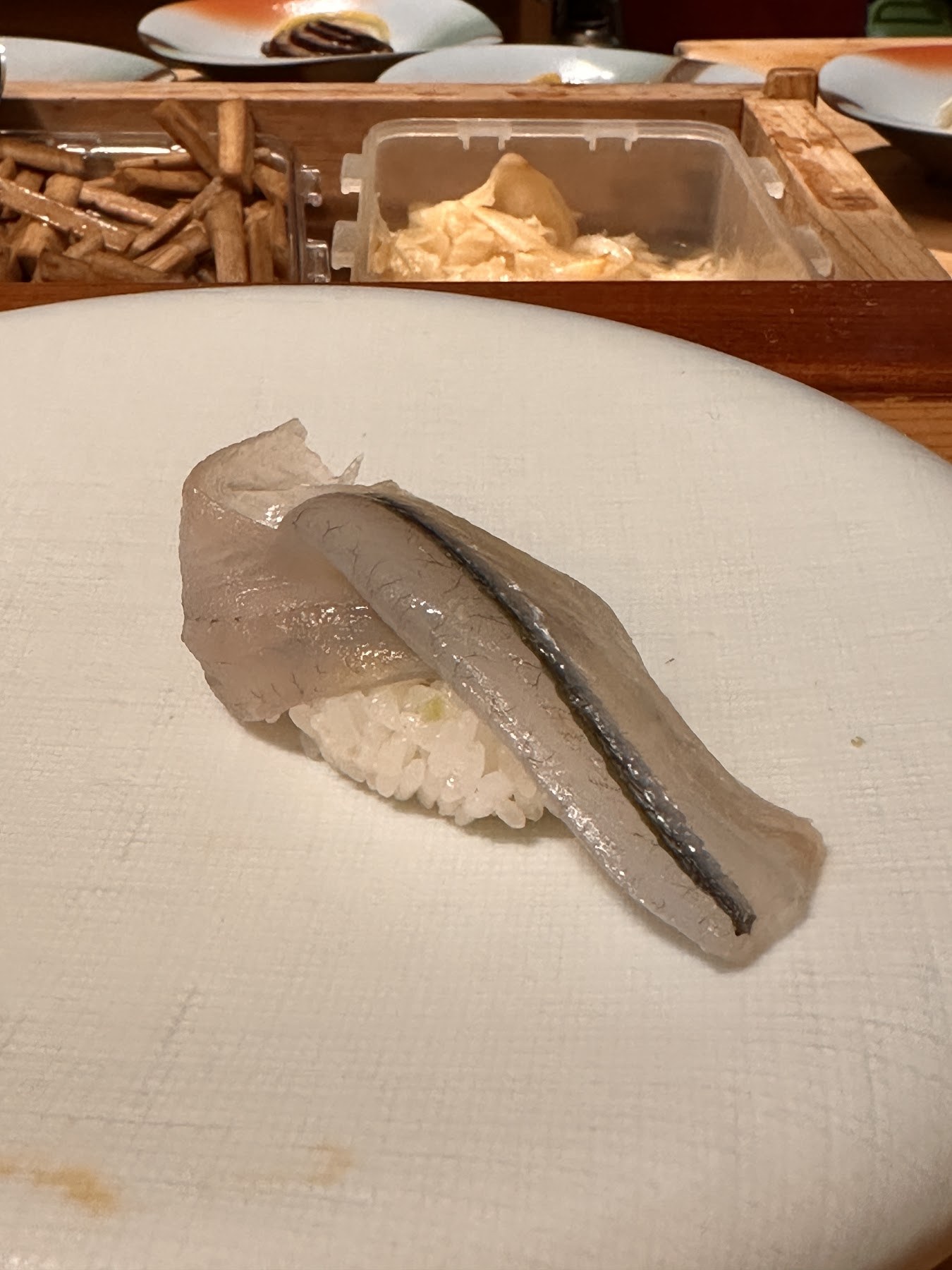 A white fish nigiri with a silver line on the skin