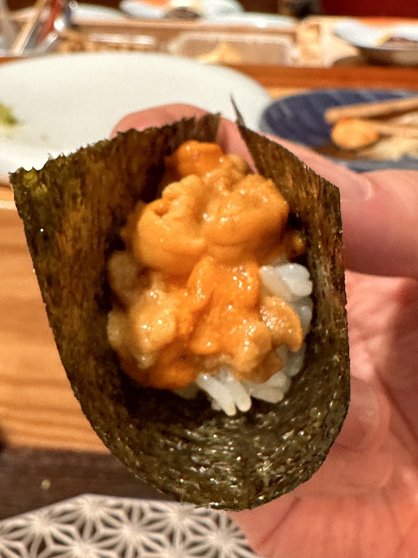 A sea urchin hand roll wrapped in nori and passed straight into your hand