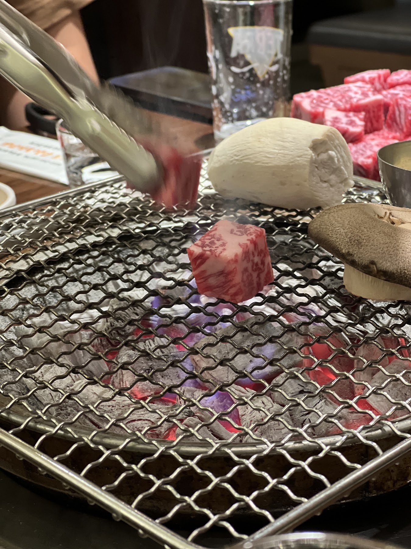 The first piece of cube-cut sirloin on the grill rack